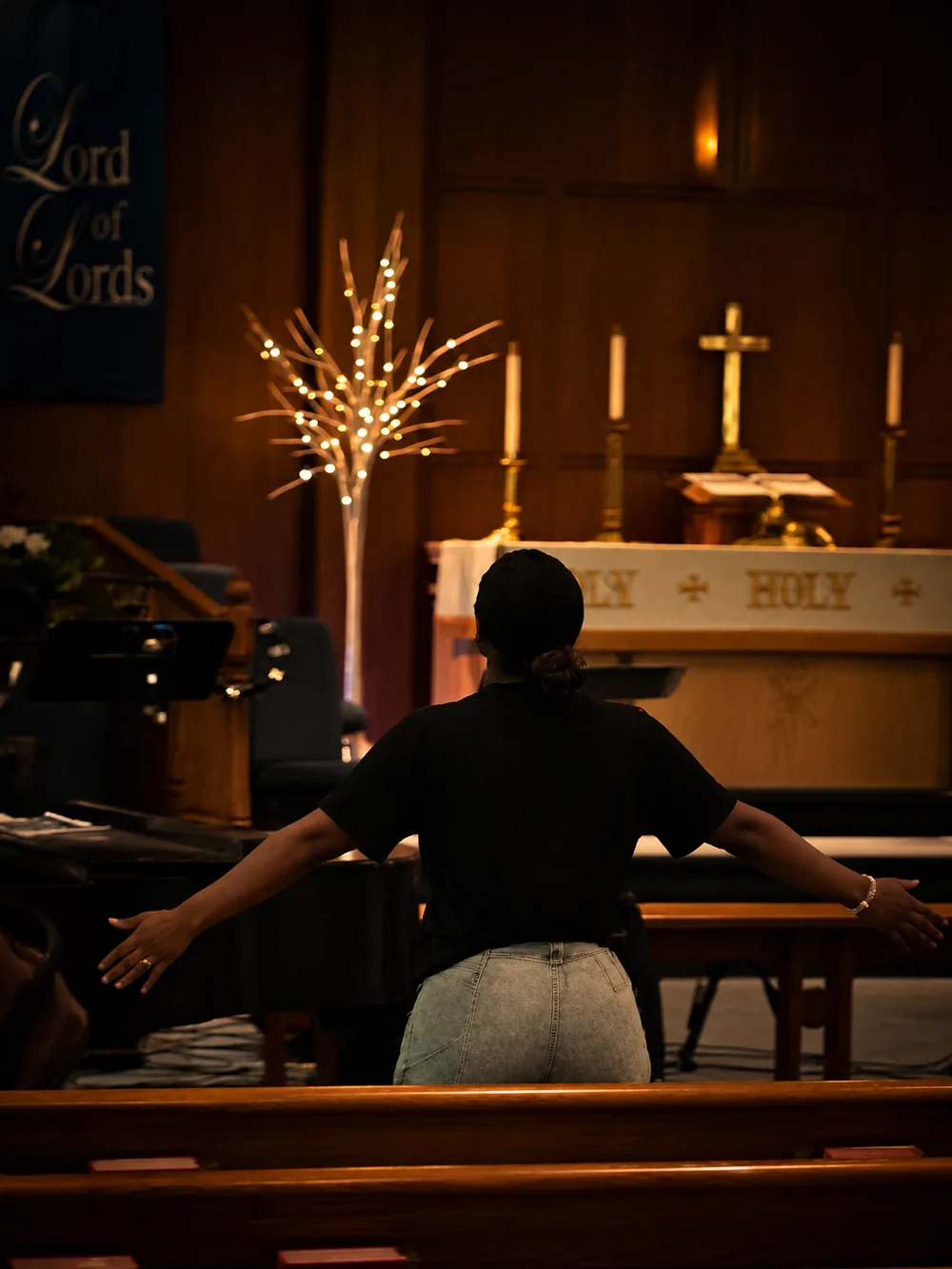 A worshipper with arms open wide before the altar during worship